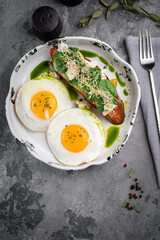 Two fried eggs for breakfast with avocado toast and salad on a plate. Healthy breakfast on the table, top view