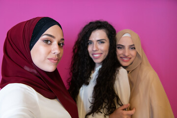 Group of beautiful muslim women two of them in fashionable dress with hijab using mobile phone...
