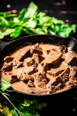Cooked liver in a frying pan with parsley.