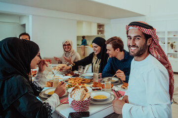  Muslim family having Iftar dinner drinking water to break feast. Eating traditional food during...