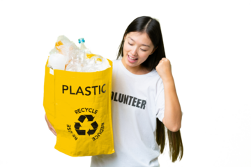Young Asian woman holding a bag full of plastic bottles to recycle over isolated chroma key background celebrating a victory