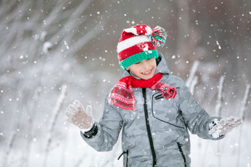 Child in winter in the forest. A little boy, a child in winter clothes, walking under the snow.