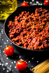 Bolognese sauce on a stone board with tomatoes, spices and dry pasta. 