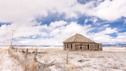 Abandoned wooden homestead on potato farm, San Luis Valley, CO, with barbed wire fence, posts,...