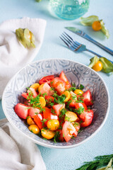 Appetizing salad with physalis, tomatoes and dill in a bowl. Vegetarian diet. Vertical view