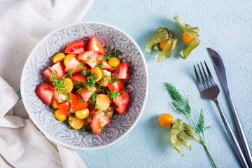 Delicious salad of tomatoes, physalis and dill in a bowl. Vegetarian food. Top view