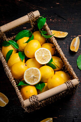 Fresh lemons with foliage in a basket. 