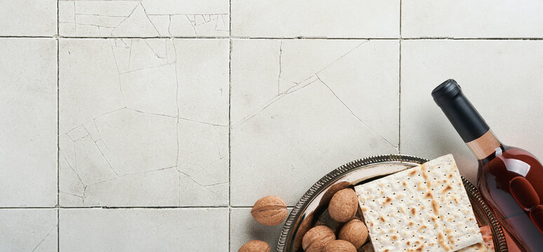Passover celebration concept. Matzah, red kosher walnut. Traditional ritual Jewish bread on old grey cracked tile countertop table background. Passover food. Pesach Jewish holiday. Banner.