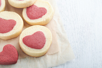 Valentines day cookies. Shortbread cookies inside a sweet red heart on parchment paper on white background. Mothers day. Womans day. Sweet holidays baking. Top view.