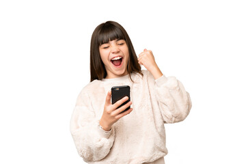 Fototapeta premium Little girl over isolated green chroma key background with phone in victory position