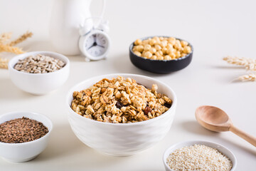 Obraz na płótnie Canvas Baked granola in a bowl and different seeds in bowls on the table. Healthy breakfast.