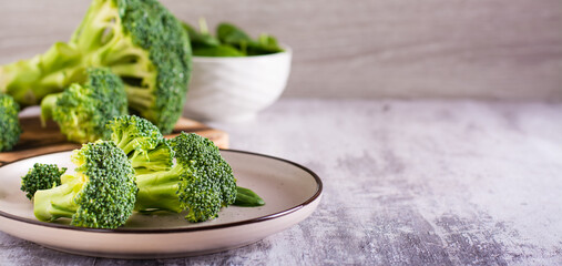 Fresh broccoli and spinach leaves on a plate on the table. Healthy food, green food. Web banner