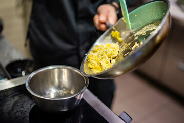 man chef cooking scrambled eggs in frying pan on kitchen