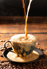 Coffee and milk, pouring latte into a black cup, dark food style photo, selective focus.