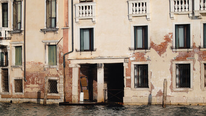Fototapeta na wymiar Ancient Venetian structure on the canals of Venice. Calm water between vein channels