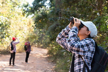 Asian boys are using binoculars to do the birds' watching in tropical forest during summer camp, idea for learning creatures and wildlife animals and insects outside the classroom.