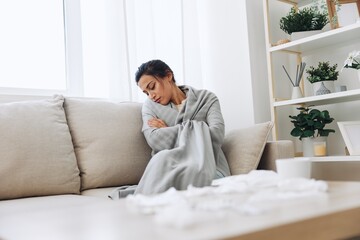 Woman cold headache runny nose and stuffy nose sitting on sofa in plaid, treatment for flu, allergies and covid-19