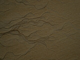 Top down close up macro of braided intertwined meandering water stream flow on sand beach in Abel...