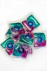A pile of colored capsules for washing clothes on a light background, close-up, selective focus.