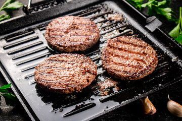 Cooking a delicious grilled burger on a pan with oil bubbles.