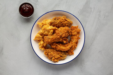 Chicken Popcorn, Wings and Tenders with BBQ Sauce on a plate on a gray background, top view. Flat lay, overhead, from above.