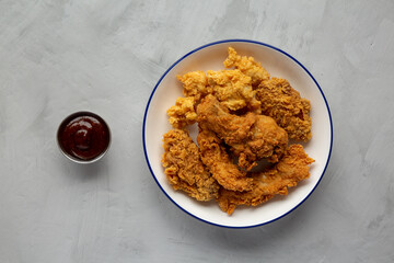 Chicken Popcorn, Wings and Tenders with BBQ Sauce on a plate on a gray background, top view. Flat lay, overhead, from above.