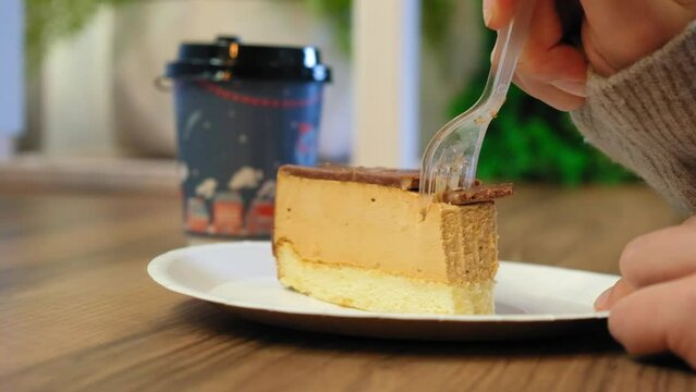 a girl in a cafe eats a cake in slow motion. cheesecake is cut with a plastic fork in a cafe in slow motion