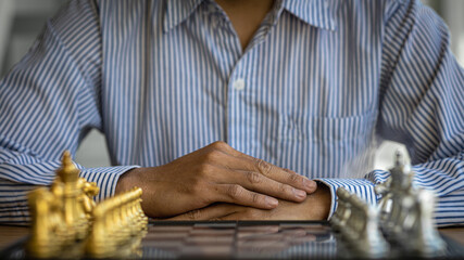 Businessman planning strategy with chess figures on wooden table.