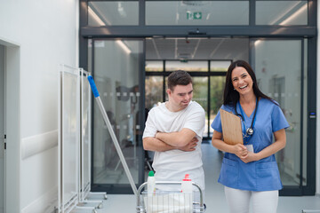 Young man with down syndrome working in a hospital as cleaner, talking to nurse, having fun....