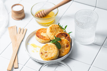 syrniki with honey on a white plate