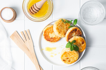 syrniki with honey on a white plate