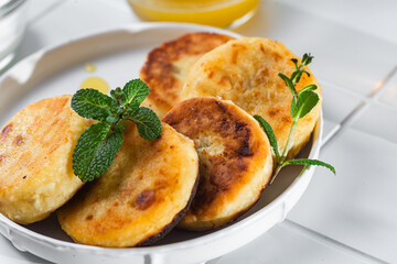 syrniki with honey on a white plate