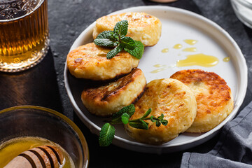 syrniki with honey on a white plate