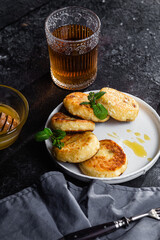syrniki with honey on a white plate