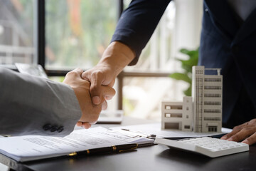 Close up shake hands, Considering buying a home, investing in real estate. Broker signs a sales...