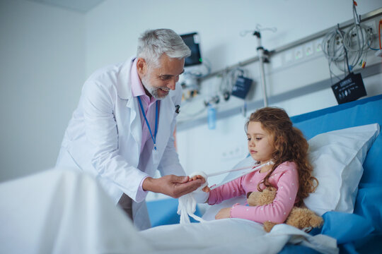 Doctor examining little girl with broken arm.