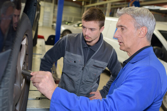 auto mechanic shows the trainee maintenance of tyre