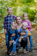 Portrait of happy mother with her four kids at forest.