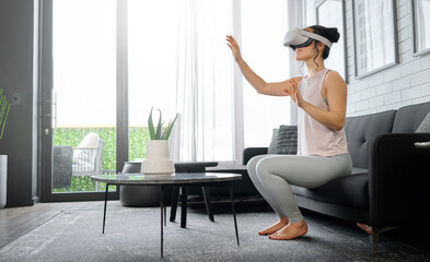 VR, metaverse and futuristic with a woman in the living room of her home using a headset to access...