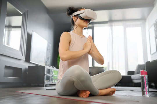 VR, meditation and fitness with a woman using a headset to access the metaverse in her home for health. Virtual reality, yoga and exercise with a young female yogi meditating in her house using 3d ai - Powered by Adobe