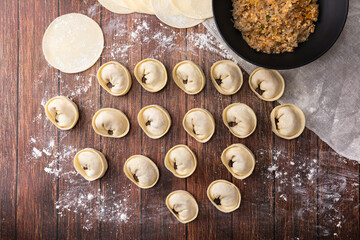 Homemade kimchi dumplings made with wheat flour and shaped into round shapes. Wood deck background, closeup viewed from above.