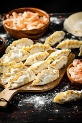 Raw dumplings gyoza with shrimp on a cutting board. 