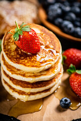A pile of pancakes with berries and honey. 