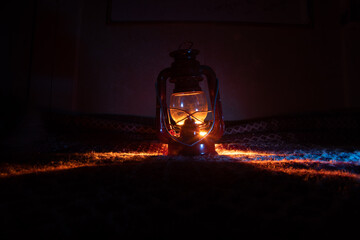 A beautiful red metal oil lamp with a warm light glow. Cozy object pjoto of a lantern.