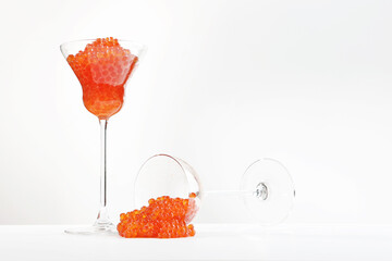 Red caviar in a tall glass. The second glass of caviar is on the table.An expensive delicacy. An exquisite snack. A useful omega.White background. Copy space.