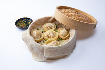 Delicious homemade Korean kimchi dumplings in a bamboo steamer over white background.