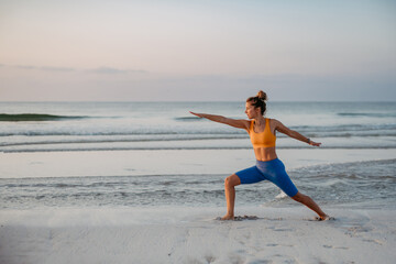 Young woman taking exercises at beach, morning routine and healthy lifestyle concept.