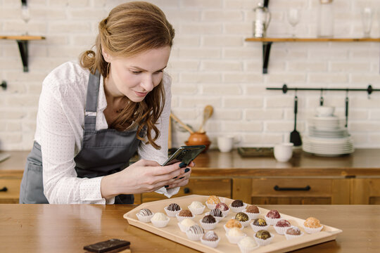 Woman takes pictures of candies on phone. Home pastry chef. Natural. Space for text