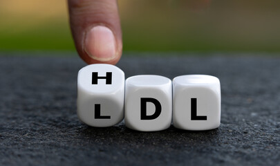 Hand turns dice and changes the abbreviation LDL (low-density lipoprotein) to HDL (high-density...