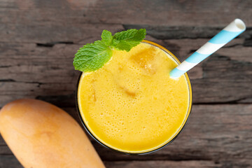 Mango smoothies orange colorful fruit juice beverage healthy high protein the taste yummy in glass on wood background from top view.
